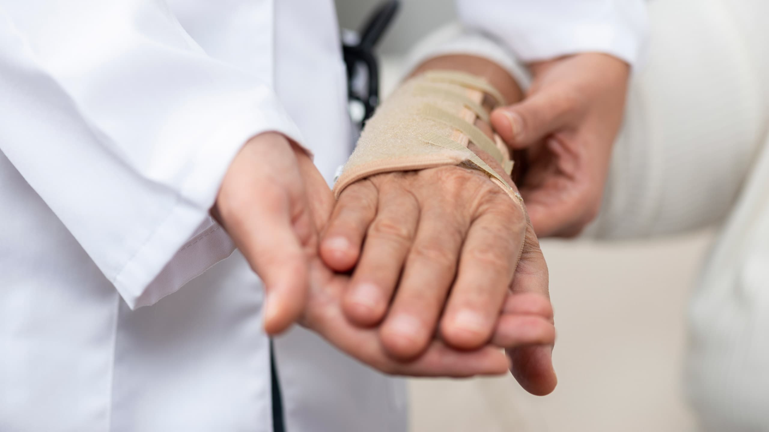 Healthcare professional wrapping injured wrist of senior woman