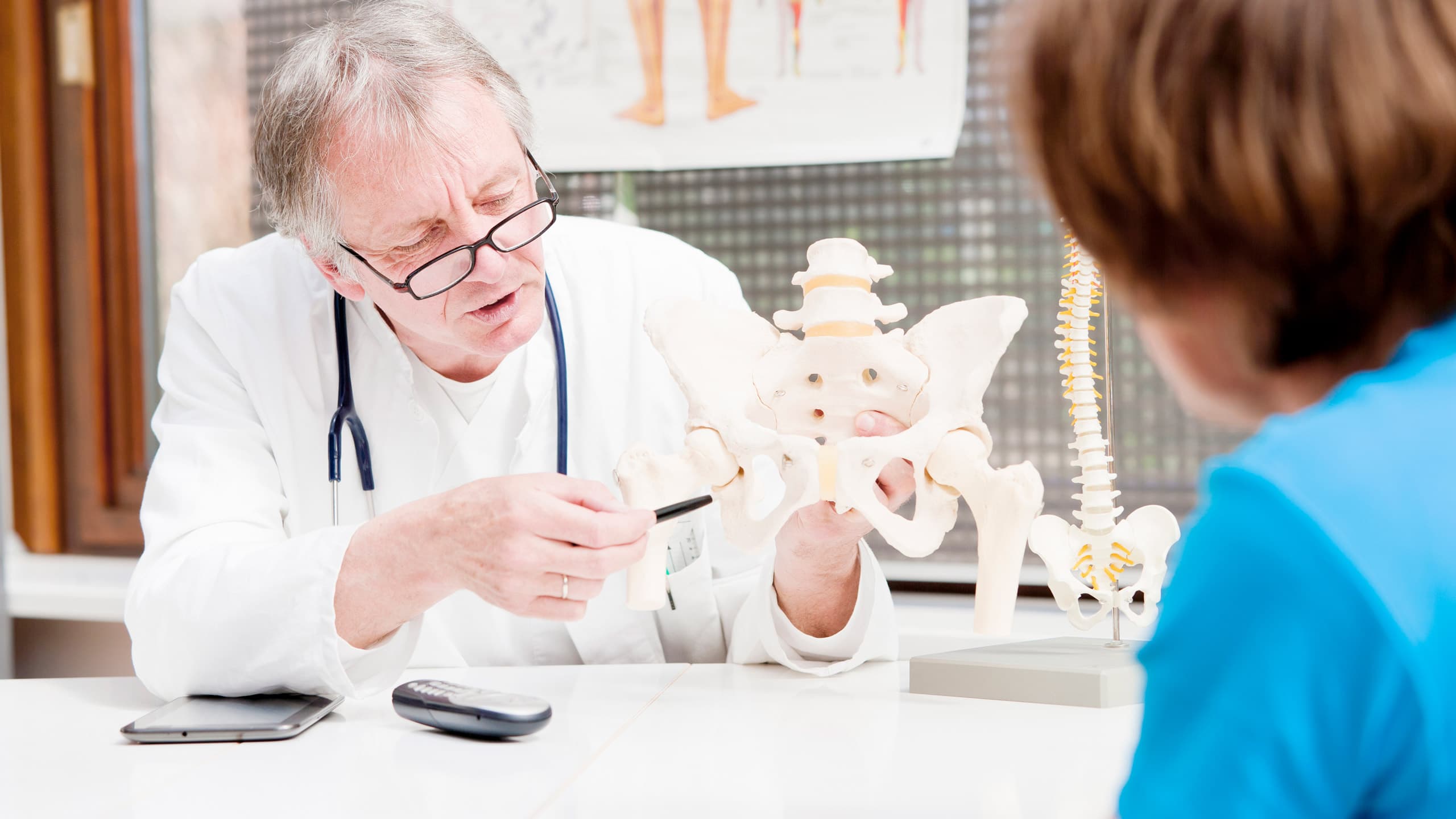 A mature orthopedist, explaining the problems of the hip to a patient