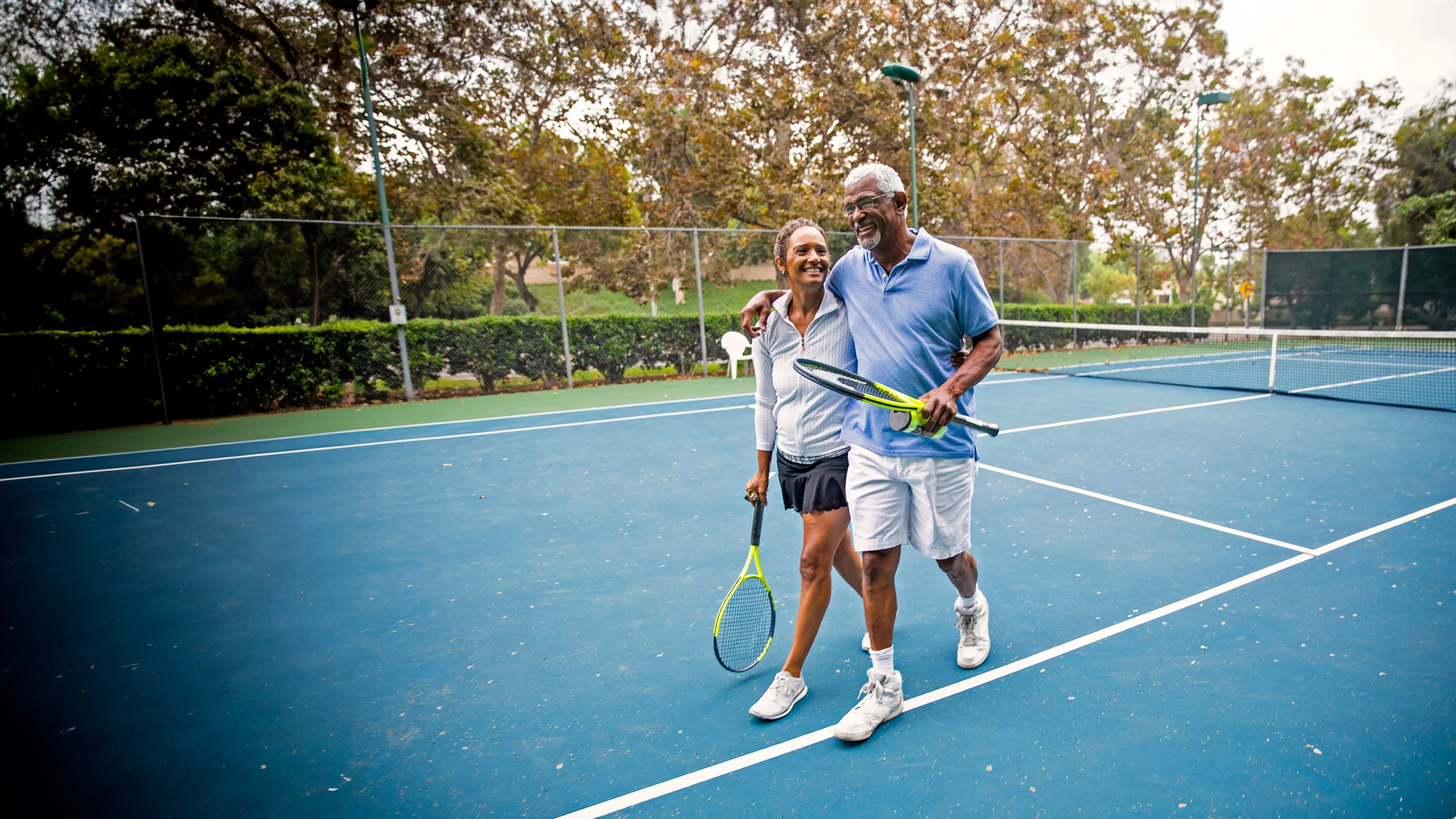 Senior couple with successful joint replacement surgery enjoying themselves after playing tennis outdoors